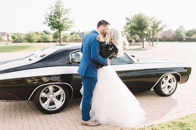 Bride and groom kissing in front of a car
