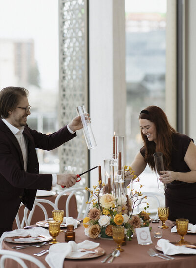 Close-up of Frid Event's owner and creative director Brittany Frid and Production Manager Lee Large sharing a joyful moment with cocktails, showcasing a fun and friendly atmosphere perfect for the creative event team in Ottawa.