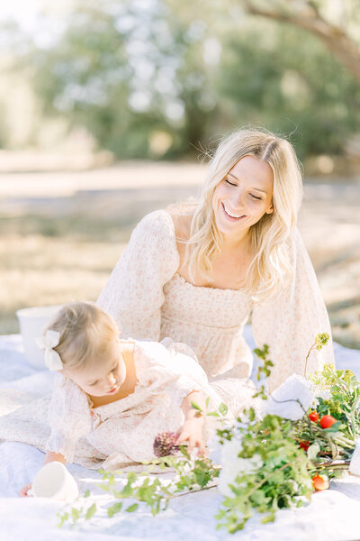 Beautiful blonde mother and daughter have a strawberry picnic