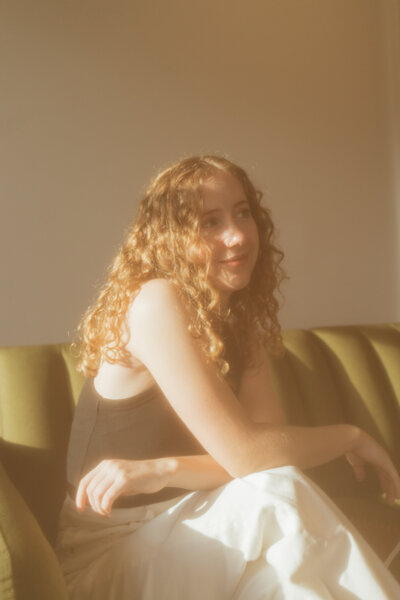 The wedding photographer, Autumn, sitting on a green couch.