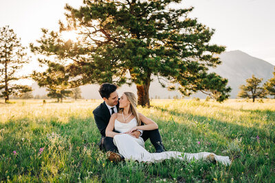 Denver Wedding Photographer captures bride and groom sitting in grass cuddling