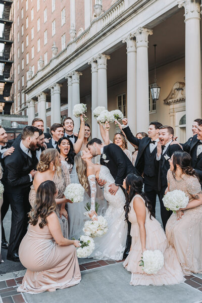 wedding party cheering as couple kisses