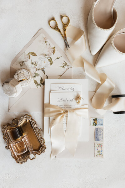 Beautiful flat lay of inviations, shoes, wedding rings, and flowers.