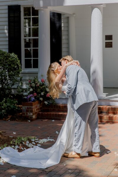 Bride and groom sharing a kiss outside Leslie-Alford Mims House wedding venue in Raleigh, NC — timeless wedding photo and video by Moments by Hiba.