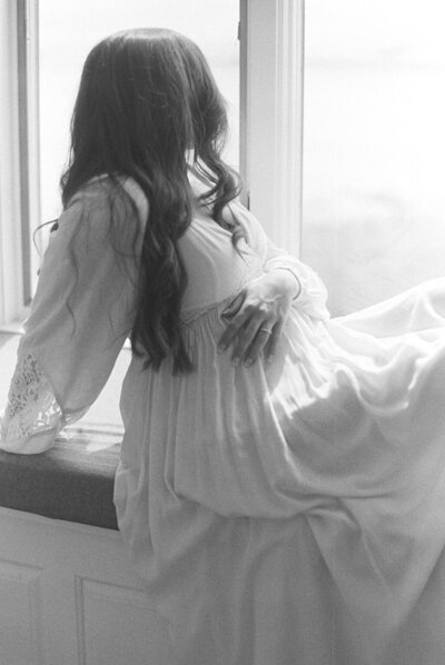 Richmond maternity photographer | black and white film image of a pregnant mother sitting on a windowsill and looking out towards the water by Jacqueline Aimee portraits