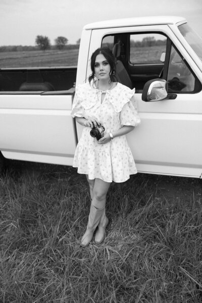 woman standing beside a vintage white truck in Kansas wearing a ruffled dress during a peaceful lifestyle session

