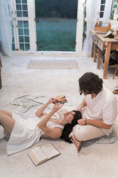 girlfriend lays in boyfriends lap while reading a book in knoxville tennessee at the holmstead studio
