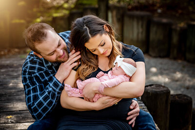 Family of three in front of a brick wall with their little daughter dancing and mom and dad laughing