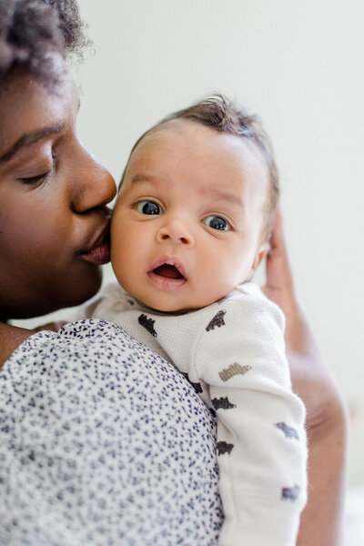 A mother kissing her newborn son during a lifestyle newborn session in Richmond, Virginia.