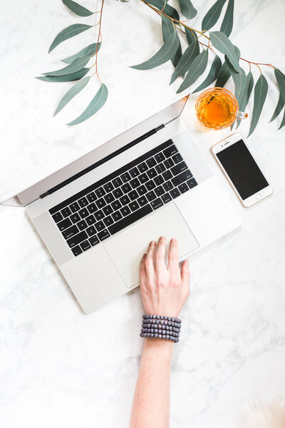 Top view of a laptop, tea and greenery