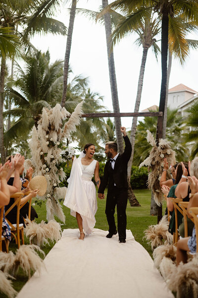 Couple celebrating and walking down the aisle of their tropical wedding