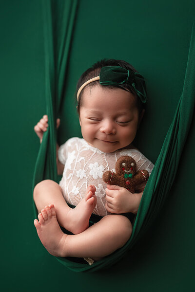 Sweet baby girl posed on a beautiful blue  backdrop during her newborn session.