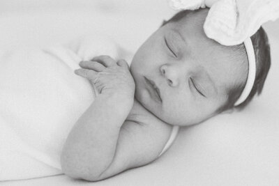 Close-up of newborn baby peacefully sleeping, wrapped in white blanket, Charlotte newborn photographer