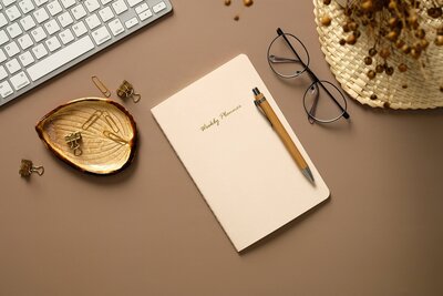 Aesthetic feminine workspace top view. Flat lay weekly planner, on a brown background