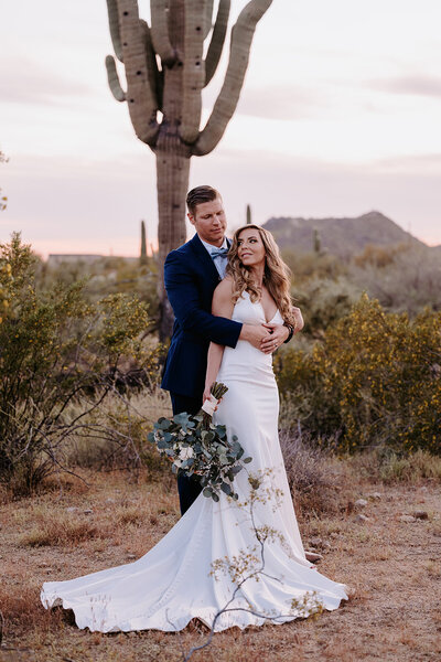 couple posing the desert at sunset with giant cactus