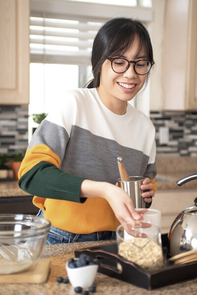 Laci measures ingredients for making oatmeal in her kitchen