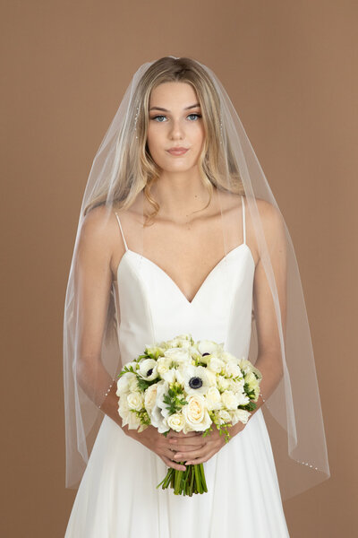 bride wearing a short rhinestone edged veil and holding a bouquet