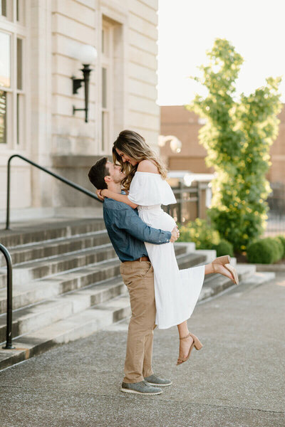 man lifting woman in front of building taken by nashville engagement photographer