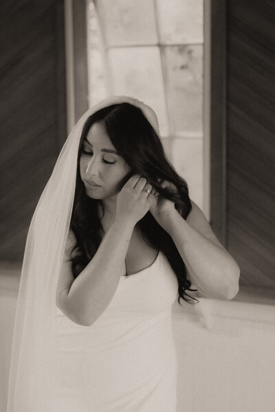 A timeless wedding portrait of a Bellingen bride putting her earring on. It is film-like and nostalgic.