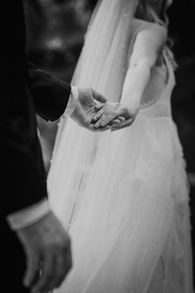 close up of bride and groom holding hands as they walk away from camera