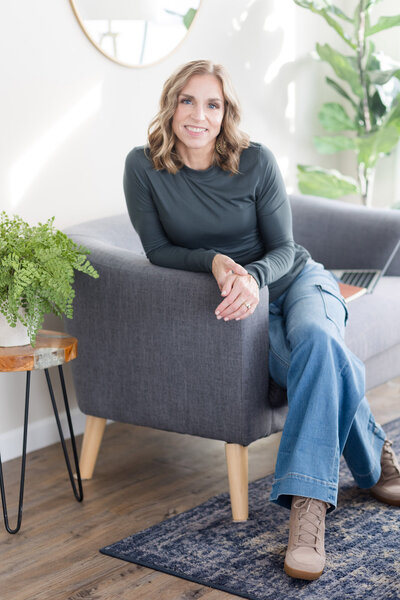 Stephanie sitting with her legs crossed on a couch