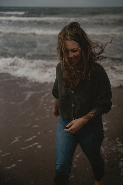 Fotograf Olivia Kylefjord går med vinden i håret längs havet