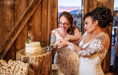 Lesbian couple cut their wedding cake inside the Barn at Evergreen memorial park in Colorado