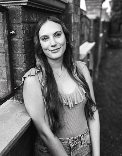 woman with dark hair and hat in front of fireplace