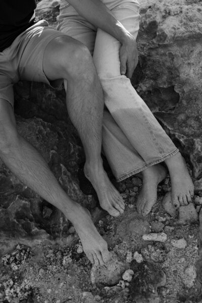 A close up of two people sitting together with one person's hand over the other's knee 