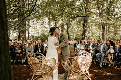 De eerste kus na de huwelijksceremonie in een romantische setting in een bos,