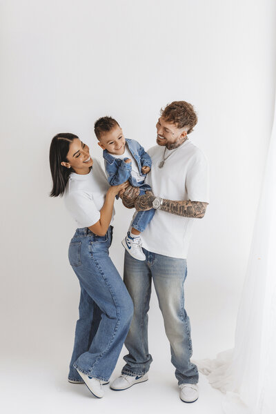 family of 3 posing in denim outfits for family studio portrait session in phoenix