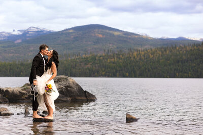 Bride and Groom standing face to face barefoot on a rock on Priest Lake