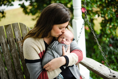Beautiful Mississippi Newborn Photography: newborn boy being kissed by his mother on porch swing