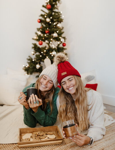 two girls in front of christmas tree holding asobu coffee mugs