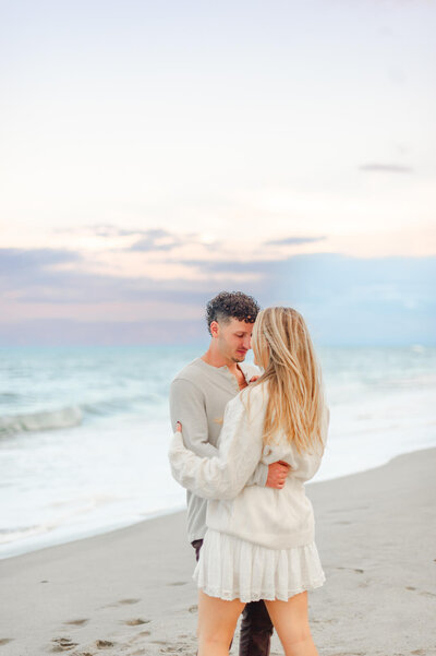 Couple newly engaged holds each other at the beach  at sunset