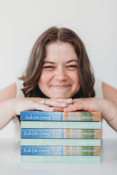 Woman smiling and resting head on stack of books