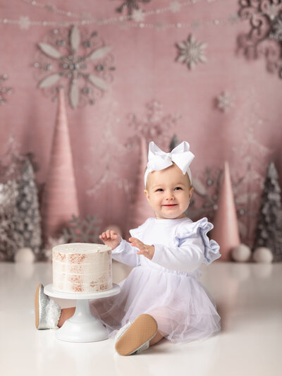 one year old girl sitting with cake for first birthday photos