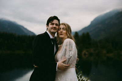 Bride and groom holding each other in their arms in the middle of the Washington mountains in front of a lake