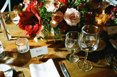 Elaborate floral bouquet sits atop table at wedding reception with name cards, silverware and glassware