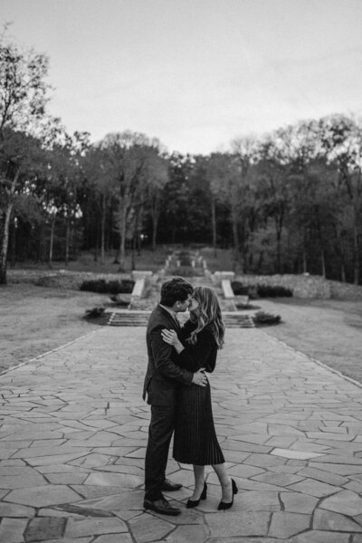 black and white image couple kissing by fountain