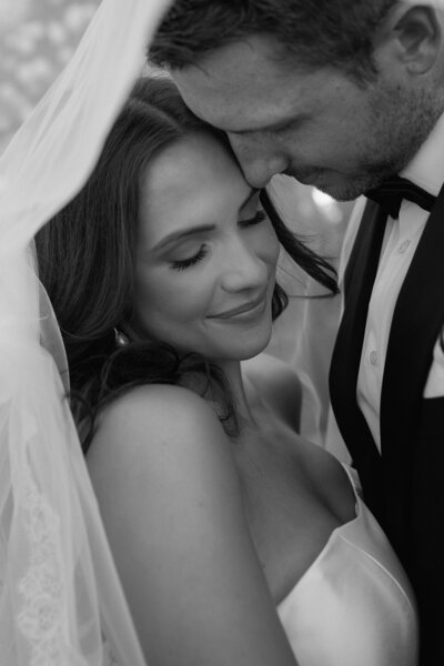 wedding couple smiling under veil