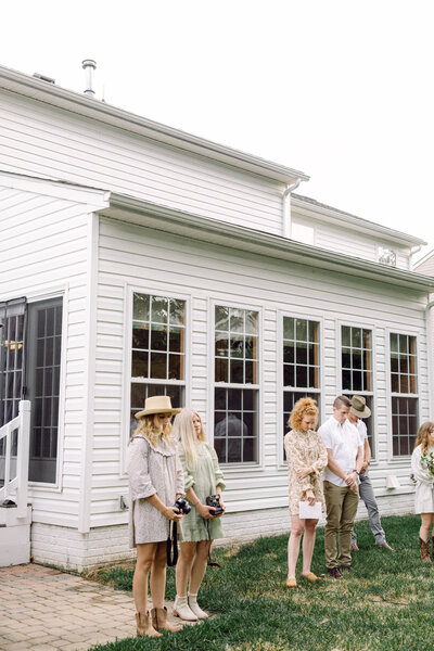 Guests stand in quiet anticipation as Peyton Curry and her husband exchange vows during their intimate backyard wedding ceremony in Richmond, Virginia. Captured by a film wedding photographer in a candid, documentary-style moment.
