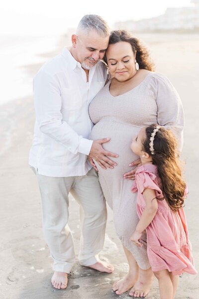 family nuzzles together on houston beach