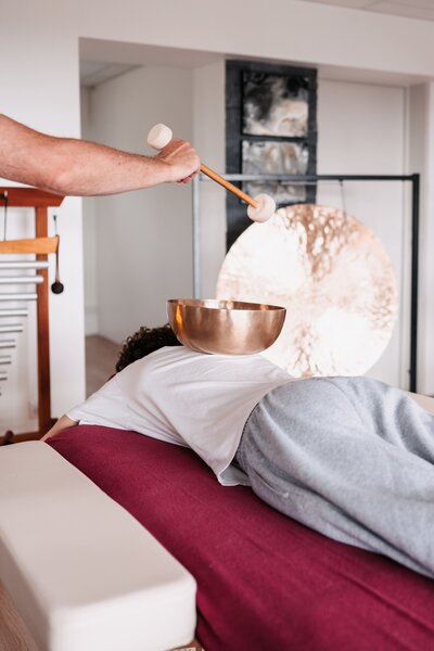 Séance de massage sonore avec utilisation d'un bol thérapeutique posé sur le dos du participants