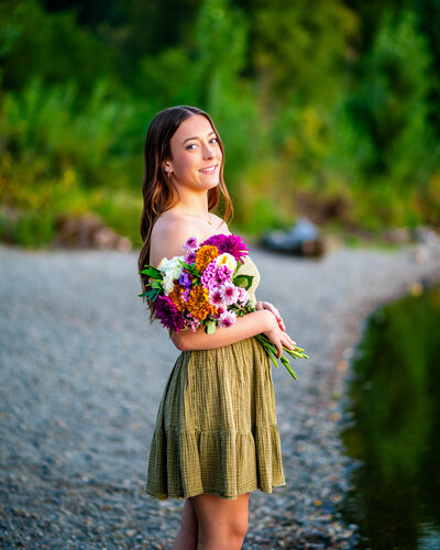 A Ballard High School senior from Seattle, Washington. She is posing for her senior photos with Mikayla Arsenian Photography. She is wearing a green dress and holding a bouquet of flowers.