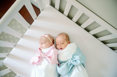 twin newborns laying together in crib