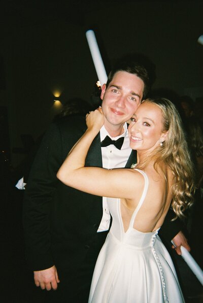 Flash film photo of bride and groom holding light sticks at wedding reception