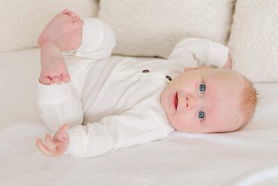 Newborn looks at flowers during photoshoot.