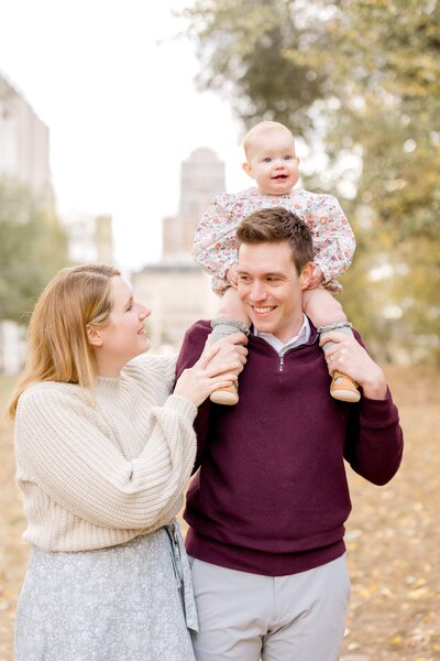 Father and mother playfully run with daughter through the field in Minneapolis Minnesota.
