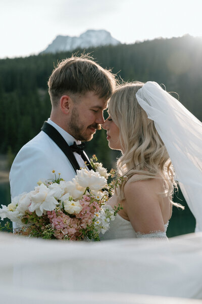 Groom and bride sharing moment together after getting eloped in Banff National Park with veil surrounding them.